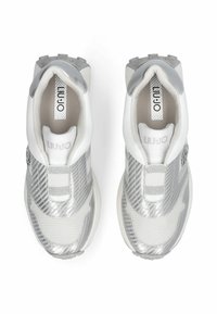 Baskets argentées et blanches avec un design texturé, comprenant des bandes élastiques et un logo sur la languette. Semelle en caoutchouc avec une bande de roulement à motif.