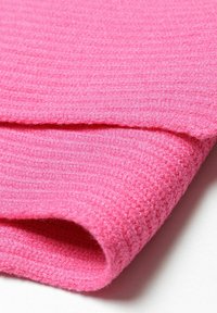 Rózsaszín bordázott szövet, amely puha, strukturált felületet mutat, látható párhuzamos vonalakkal, összehajtva, hogy a mélységet és az anyag szerkezetét szemléltesse.