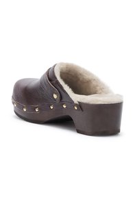 Zoccolo in pelle marrone con suola in legno, chiodini dorati lungo il bordo e un morbido rivestimento interno in pelliccia di colore crema.