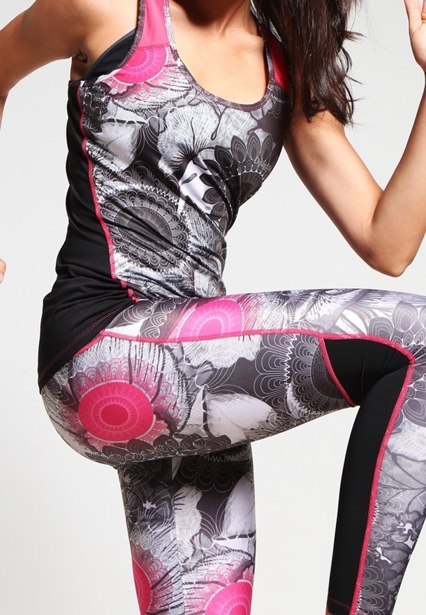 Zwart en roze sportoutfit met een tanktop met bloemenpatronen en leggings met opvallende roze accenten, gemaakt van rekbare stof.