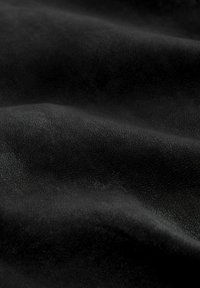 Sort ruskindsmateriale med en let struktureret overflade, der viser bløde folder og en subtil glans, egnet til forskellige anvendelser.