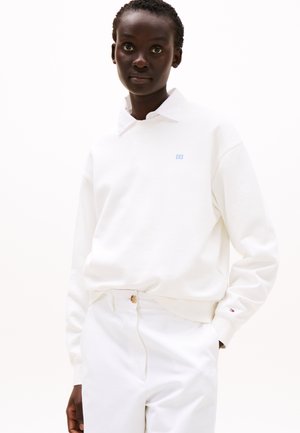 Hvit bomulls sweatshirt med en blå logo, med kragehals og ribbede mansjetter, kombinert med hvite bukser, som viser et enkelt design.