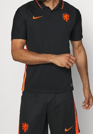 Polo nero Nike con accenti e logo arancioni, caratterizzato da un design texturizzato e un colletto classico. Abbinato a pantaloni corti coordinati.