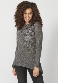 Dunkelgrauer Cowl-Neck-Pullover mit Melange-Textur, der auf einer Seite mit weißer floraler Bestickung und einem leicht asymmetrischen Saum versehen ist.