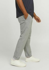 Gray pants with a slim fit, side pockets, cuffed hems, paired with white sneakers. Worn with a navy polka-dot shirt, smooth texture.