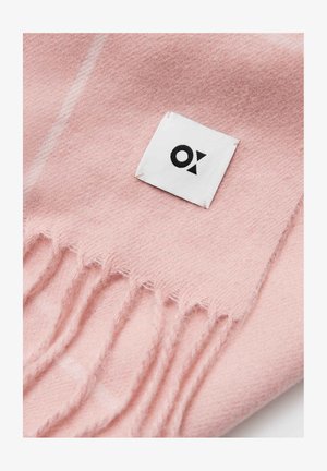 Miękki różowy szalik z wełny, z frędzlami na brzegach oraz małą białą metką z czarnym logo, ukazujący gładką strukturę i prosty design.