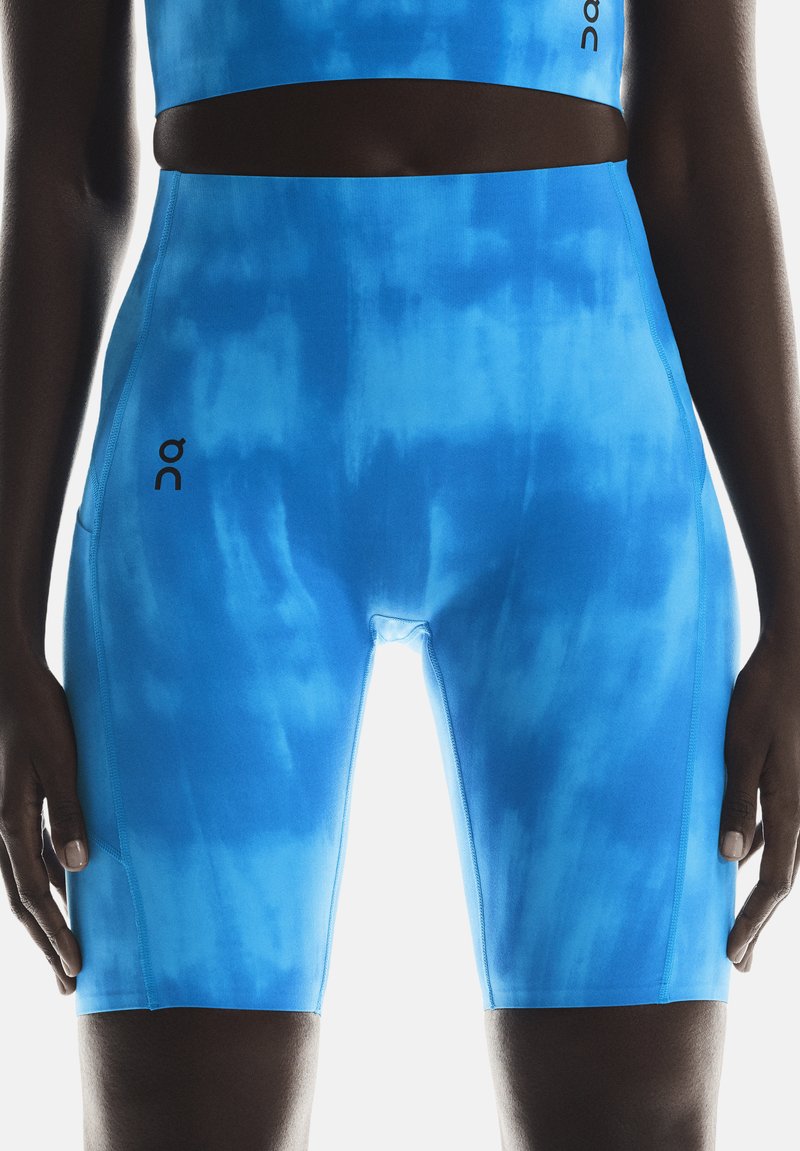 Plave tie-dye kratke hlače od rastezljivog materijala, s visokim strukom i bočnom džepom. Logo brenda vidljiv na lijevom bedro.