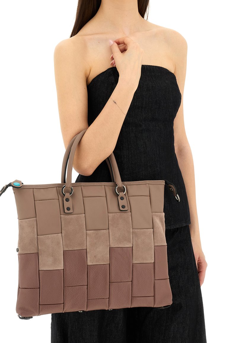 Borsa tote intrecciata marrone in un mix di pelle e suede, con doppi manici e dettagli di metallo, esposta su uno sfondo scuro.