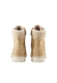 Tan suède enkelboots met een nepbont kraag. Voorzien van zijknippers, een chunkyzool in het wit en een gladde textuur. Casual ontwerp.