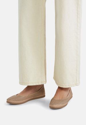 Bailarinas beige perforadas con superficie texturizada y puntera redonda, combinadas con pantalones de pierna ancha de color claro.