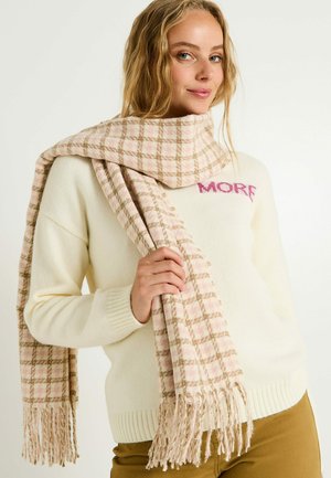 Bufanda a cuadros en tonos rosa y beige con flecos, hecha de un tejido suave, colocada alrededor del cuello, combinada con un suéter color crema.