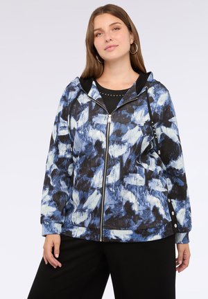 Hoodie mit einem blau-weißen abstrakten Muster auf schwarzem Hintergrund, mit einem Frontreißverschluss und seitlichen Druckknopfdetails.