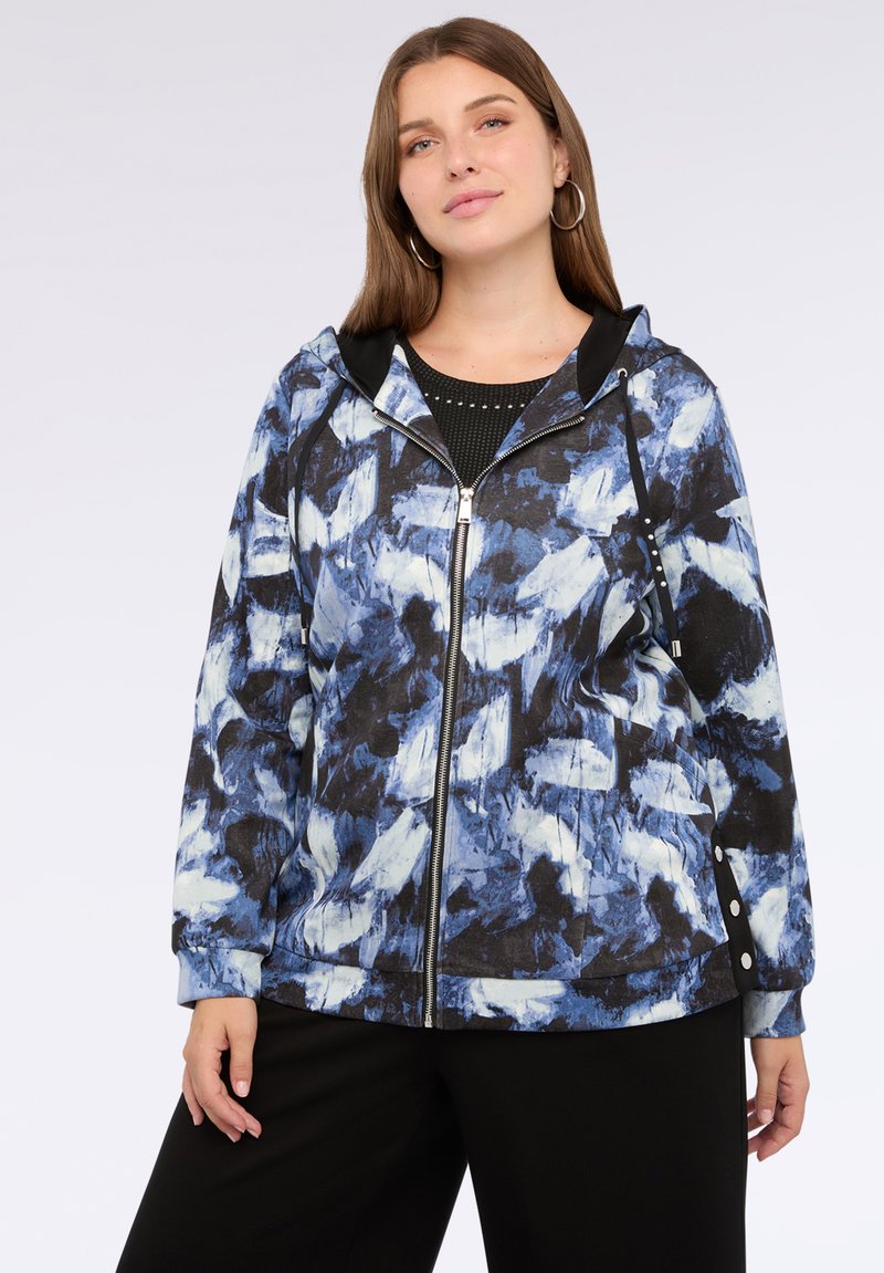 Giacca con cappuccio caratterizzata da un motivo astratto blu e bianco su sfondo nero, con zip frontale e dettagli con bottoni laterali.