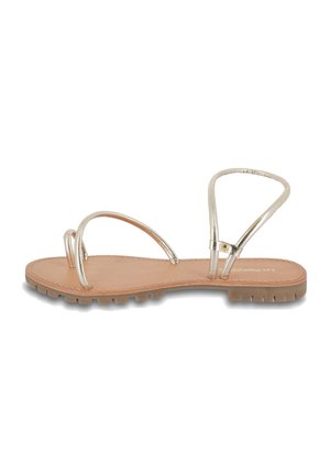 Gold metallic sandals with thin straps and a flat tan sole. Features a minimalist design with an adjustable ankle strap and textured sole.