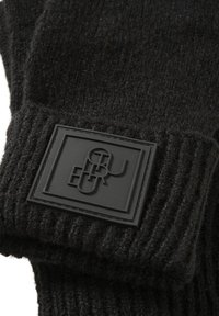 Schwarze gestrickte Handschuhe haben eine gerippte Textur und ein auffälliges rechteckiges gummiertes Logopatch mit erhabenem Schriftzug.