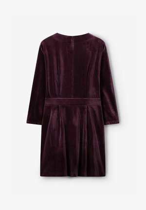 Robe en velours de couleur bordeaux foncé, coupe droite, manches longues et taille ceinturée. Caractérisée par une texture lisse et un détail de jupe plissée.