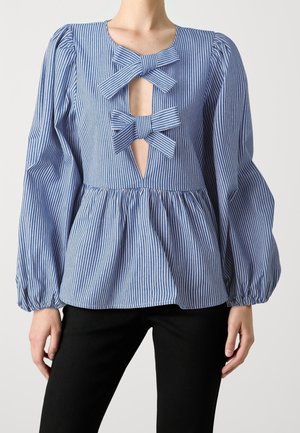 Blå og hvid vertikalt stribet bluse med puflange ærmer, peplumtalje og to sløjfebånd over en frontudskæring.