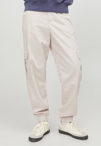 Světle růžové cargo kalhoty s elastickými manžetami a bočními kapsami, vyrobené z měkké tkaniny, s volným střihem a hladkým povrchem.