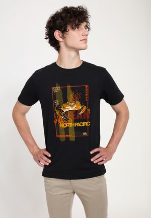 Sorte bomulds t-shirt med et farverigt krabbe grafik med teksten "NORTH PACIFIC" i gul og rød, mod en tekstureret baggrundsdesign.
