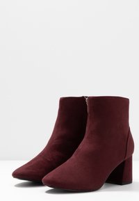 Burgundy anklarboots i mjuk mocka med spetsig tå och blockklack. Har en sidsdragkedja för enkel påklädning.