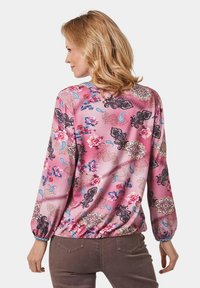 Langärmlige Bluse aus pinkem Stoff mit floralem und Paisley-Muster. Verfügt über einen elastischen Taillenbund und schmaler geraffter Ärmelabschluss für einen strukturierten Look.