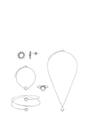 Zilveren sieraadset met zonvormige ontwerpen omvat oorknopjes, armband, ring, slavenarmband en ketting met kettingsluiting op witte achtergrond.