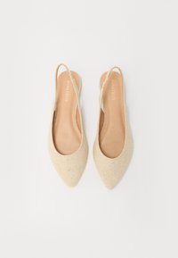 Chaussures plates à talon ouvert beige avec un design à bout pointu, fabriquées en tissu texturé, dotées d'une semelle intérieure en cuir lisse et d'accents minimalistes.