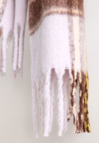 Ullsjal med en övergång av ljusrosa, brunt och gult. Har fransiga kanter och en mjuk, texturerad yta.