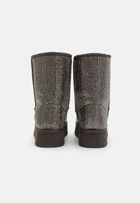 Brune mid-calf støvler med et teksturert vevd mønster. Myk stoffoverdel og gummisåle. Rund tå og sømdetaljer.