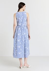Gestreiftes blaues Midikleid mit weißem Blumenmuster. Ärmellos, geraffte Taille und fließender Rock. Glattes Gewebe mit leichter Textur.