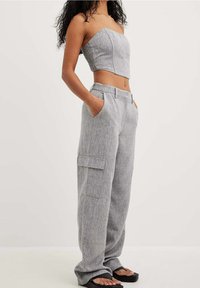 Lichtgrijze cropped strapless top met een textuurafwerking, gecombineerd met losse, hoogstaande cargobroek met zijzakken en een rechte pasvorm.