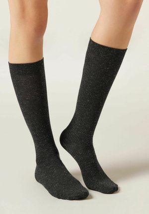Svarta knähöga strumpor med en melerad textur, med en kontrasterande ribbad mudd. Tillverkade av mjukt, elastiskt material för komfort.