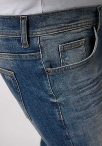 Mörkblå denimjeans med klassisk passform, med synlig sömnad, fem fickor inklusive en liten myntficka, och lätt blekning.