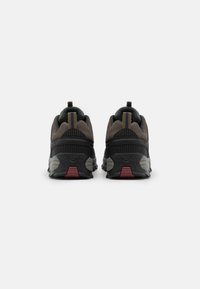 Herresneakers i sort med grå og brune detaljer. Har en tekstureret overdel, polstret krave og en robust gummisål med røde detaljer.