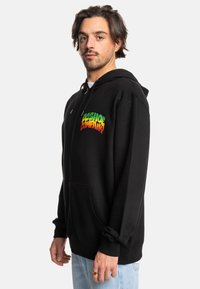 Black zip-up hoodie featuring a colorful gradient logo "LOS SHOE COMPANY" on the left chest, with a drawstring hood and front pockets.