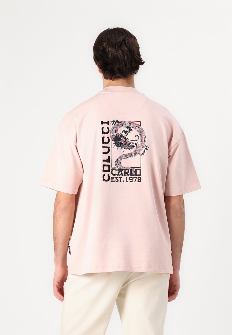 Pink short-sleeve T-shirt featuring a graphic design of a dragon and text on the back. Made of soft fabric with a relaxed fit.