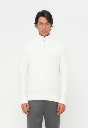 White knit sweater with a high collar and half-zip closure. Features ribbed cuffs and waistband. Smooth texture, minimalistic design.