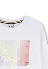 Witte t-shirt met ronde halslijn, voorzien van drie verticale pastelkleurige panelen en een gouden spikkelverf detail aan de voorkant.
