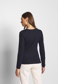 Tumesin pikkade varrukatega topp pehmest ja hingavast kangast. Liibuv disain ümmarguse kaelusega. Elegantne, minimalistlik stiil ilma lisadeta või mustriteta.