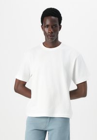 Hvid bomulds t-shirt med korte ærmer, rund halsudskæring og afslappet pasform. Enkelt design uden mønstre eller synligt hardware.