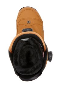 Bota de snowboard DC en cuero marrón, con forro negro suave, herrajes circulares y una suela texturizada. Diseño simple con acentos mínimos.