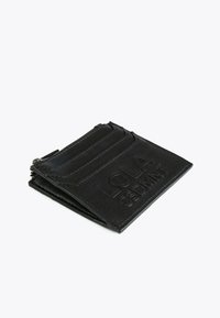 Musta nahkainen korttikotelo, jossa on kohokuvioitu "LOLA CSDMNT" -teksti, useita korttipaikkoja ja vetoketjullinen kolikkotasku valkoisella taustalla.