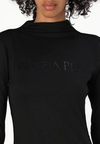 Camisa preta de manga longa com um colarinho alto, textura suave e adornada com o nome "PATRIZIA PEPE" em acentos brilhantes.