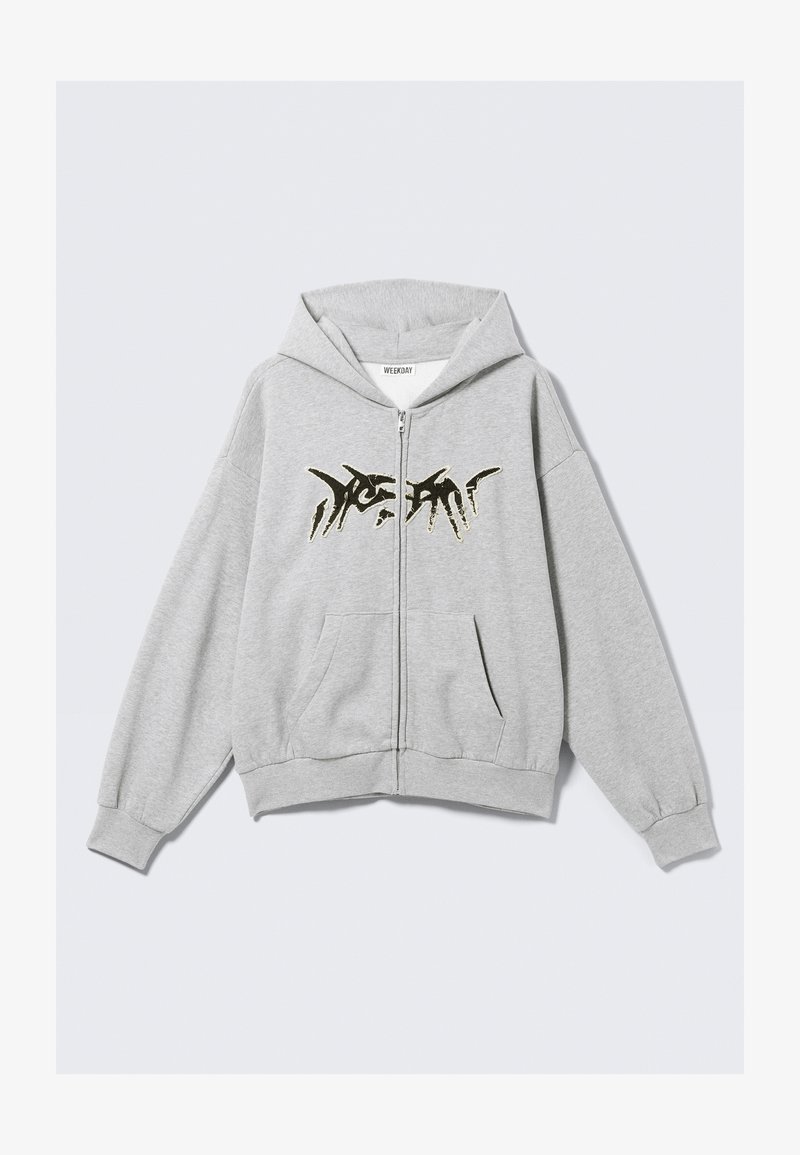 Sweat à capuche gris clair zippé avec un motif abstrait noir sur la poitrine, des poches avant, et des poignets et ourlet côtelés.