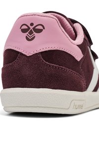 Bordeauxmocka sneakers med en rosa läderbakplatta, vita detaljer och texturerad gummi sula. Har en logotyp på hälen. Rundad form.