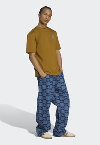 Brown cotton t-shirt with a small chest logo, paired with blue patterned wide-leg pants featuring a repeated logo design.