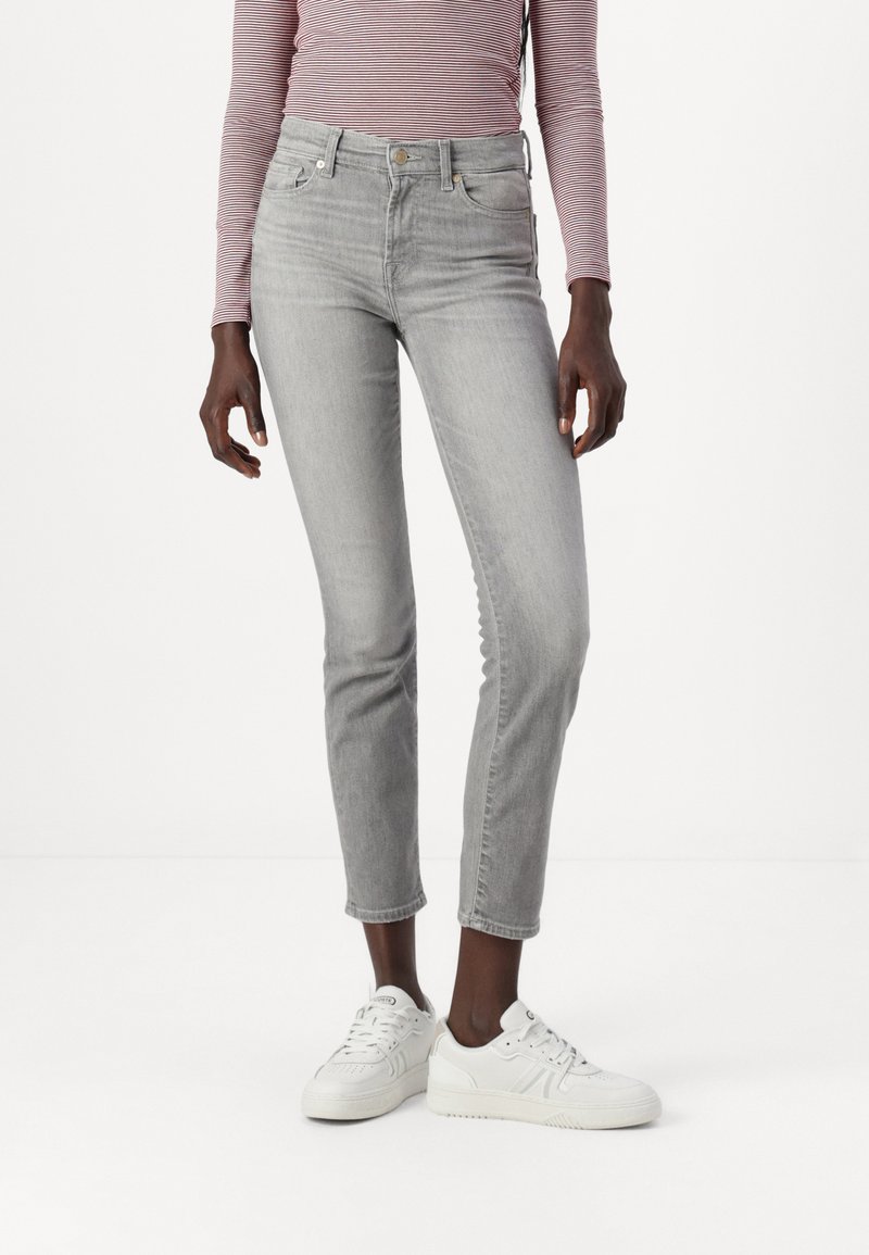 Grijze denim jeans met een slim fit en een cropped lengte, uitgerust met vijf zakken en een knoopsluiting, gedragen met witte sneakers.