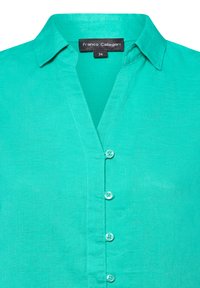 Turquoise overhemd met knopen, met een kraag en een voorflap met zes bijpassende knopen. Stof heeft een gestructureerde afwerking.