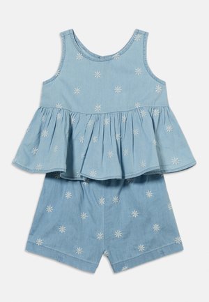 Top sans manches bleu clair avec basque et short assorti, tous deux ornés de motifs floraux brodés blancs.