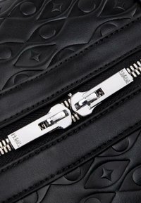 Black embossed leather with geometric patterns, featuring a silver zipper with dual metal pulls and metallic teeth.